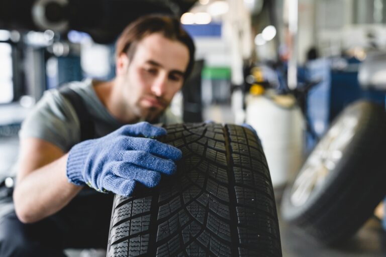 Mechanik kontroluje opotrebenie pneumatiky v autoservise.