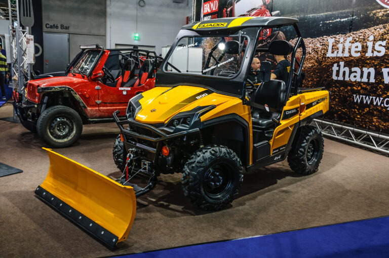 Dve terénne štvorkolky ATV s rozdielnymi evidenčnými tabuľkami, žltou a bielou, zaparkované vedľa seba.